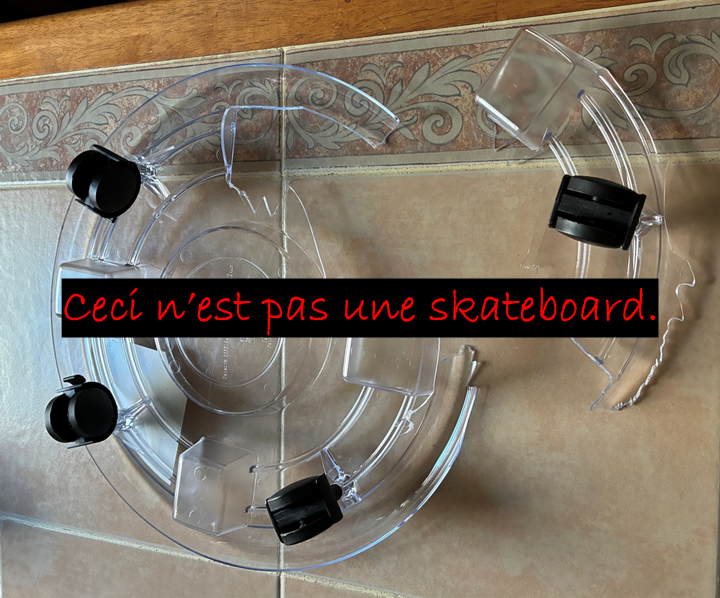 A broken plant caddy is on a table. The phrase "this is not a skateboard" in French overlays the image